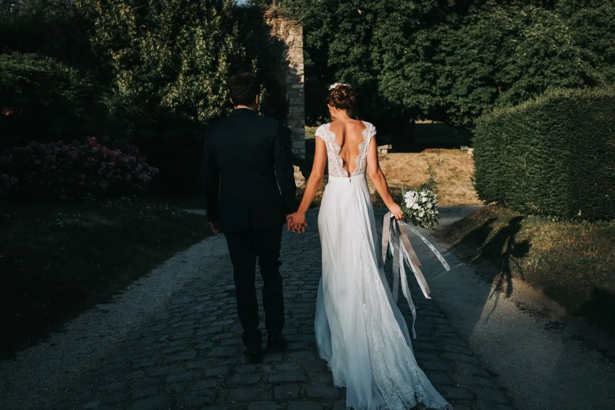 mariés qui marche de dos, avec un bouquet de fleur à la maison